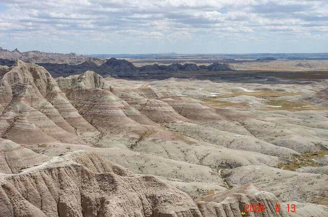 A wide view of jagged Badlands spires under a cloudy sky