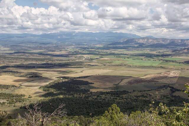 A wide valley view from Wetherill Mesa overlooking farmland and distant mountains under a cloudy sky