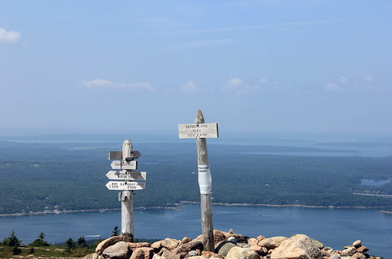 Trail signs atop Sargent Mountain, with Somes Sound and the surrounding hills spread out below