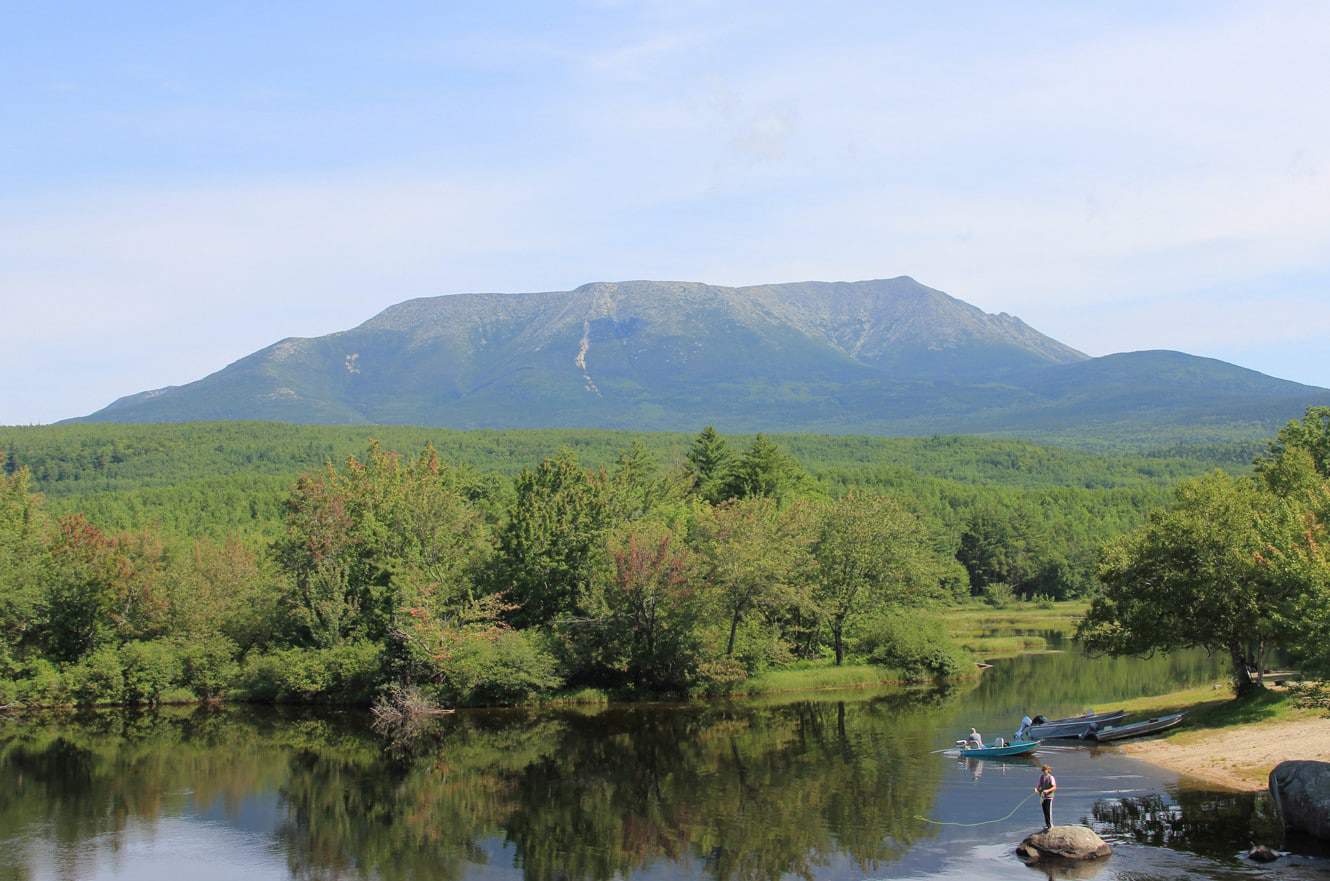 Mount Katahdin rising above the Penobscot River, with anglers fishing from the bank