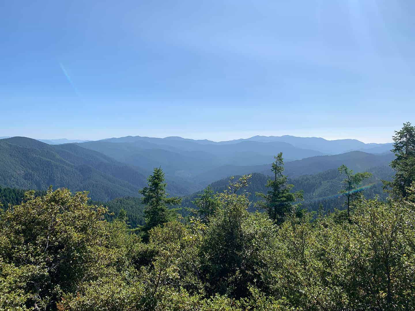 A hazy panoramic view of forested mountain ridgelines fading into the distance