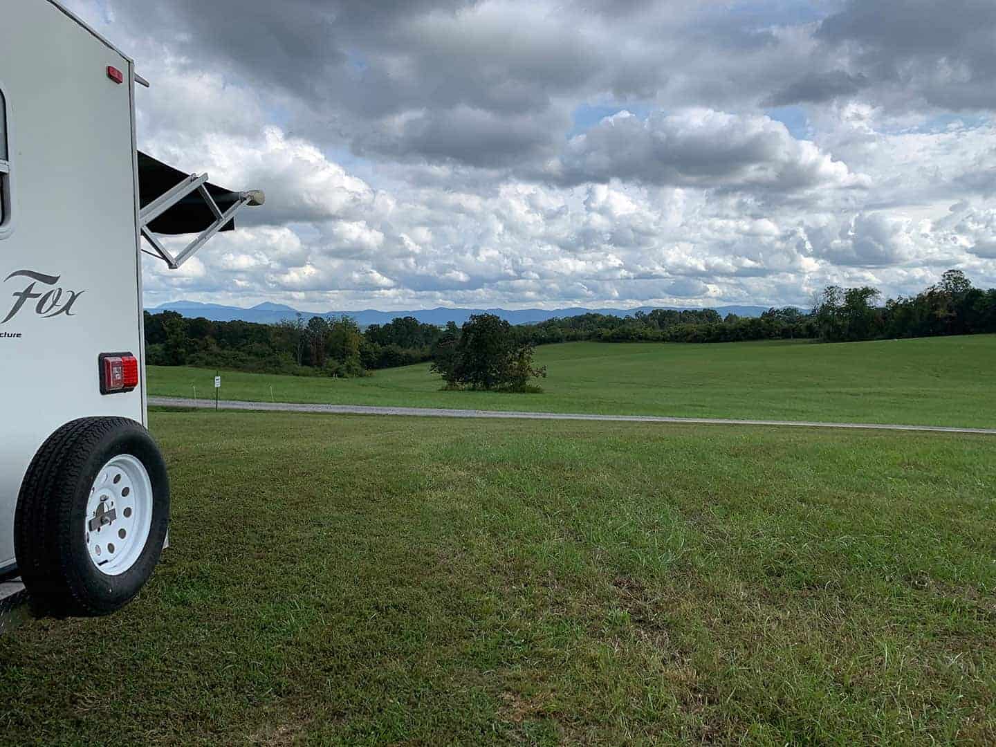 The RV parked in a grassy field at Marceline Vineyards, mountains in the distance