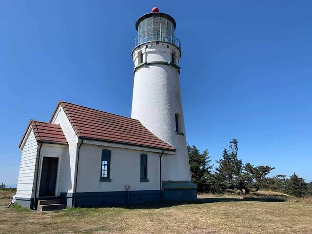 Cape Blanco Lighthouse and keeper's quarters from another angle, with wind-shaped trees nearby