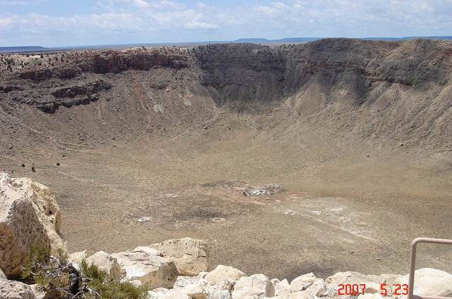 The vast crater floor of Meteor Crater, ringed by layered rock walls