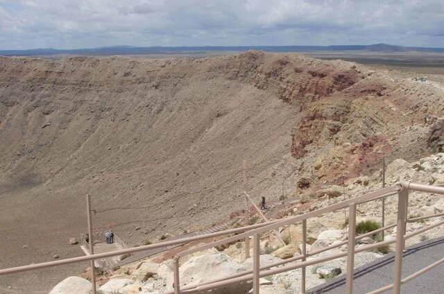 Visitors on a viewing platform overlooking the steep walls of Meteor Crater