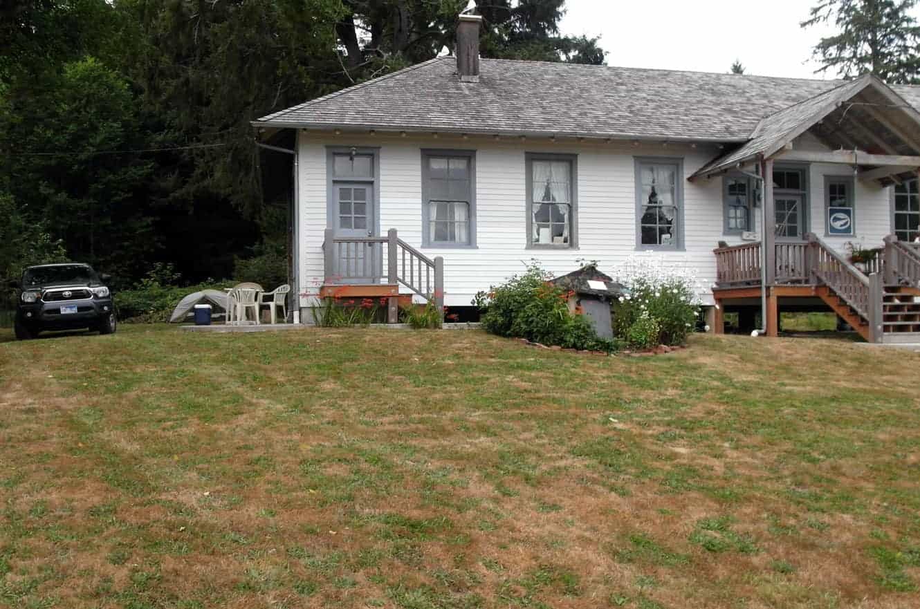 The white clapboard quarantine station house with a truck parked out front and a tent pitched on the lawn