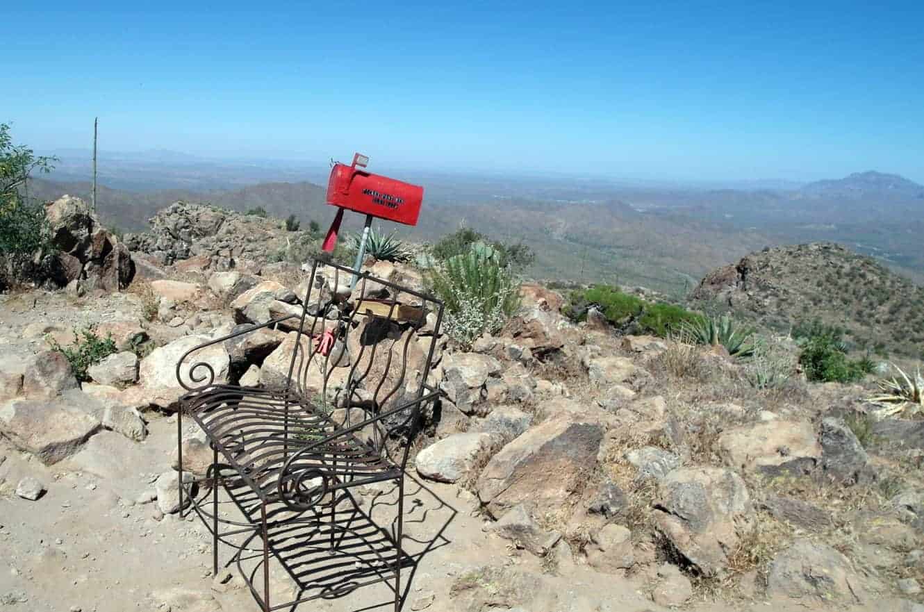 A wrought iron bench and a red mailbox left by hikers on the mesa top of Picketpost Mountain, overlooking the desert valley