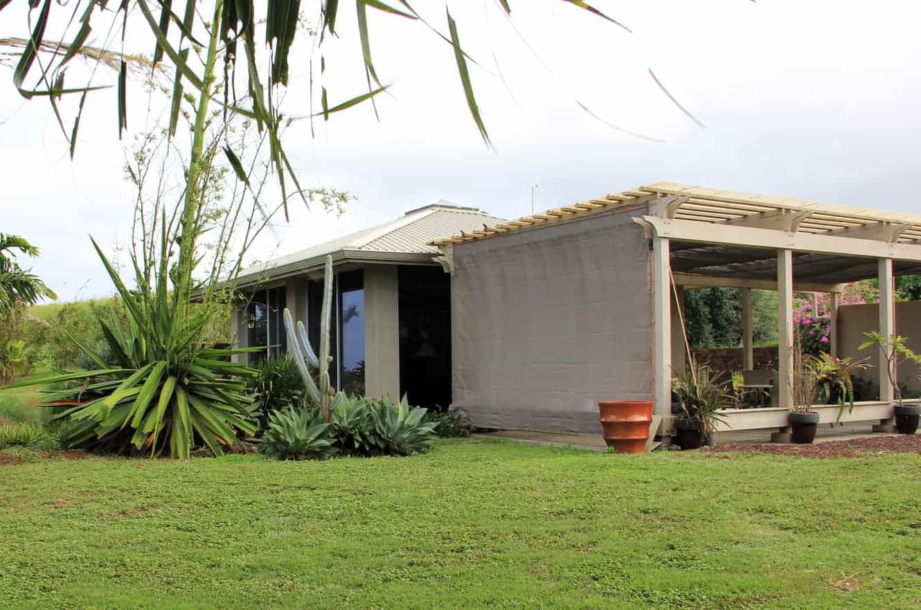 The vacation rental's exterior with a covered lanai, potted plants, and tropical landscaping